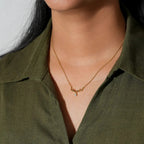 Person wearing a gold necklace with a green shirt on a white background